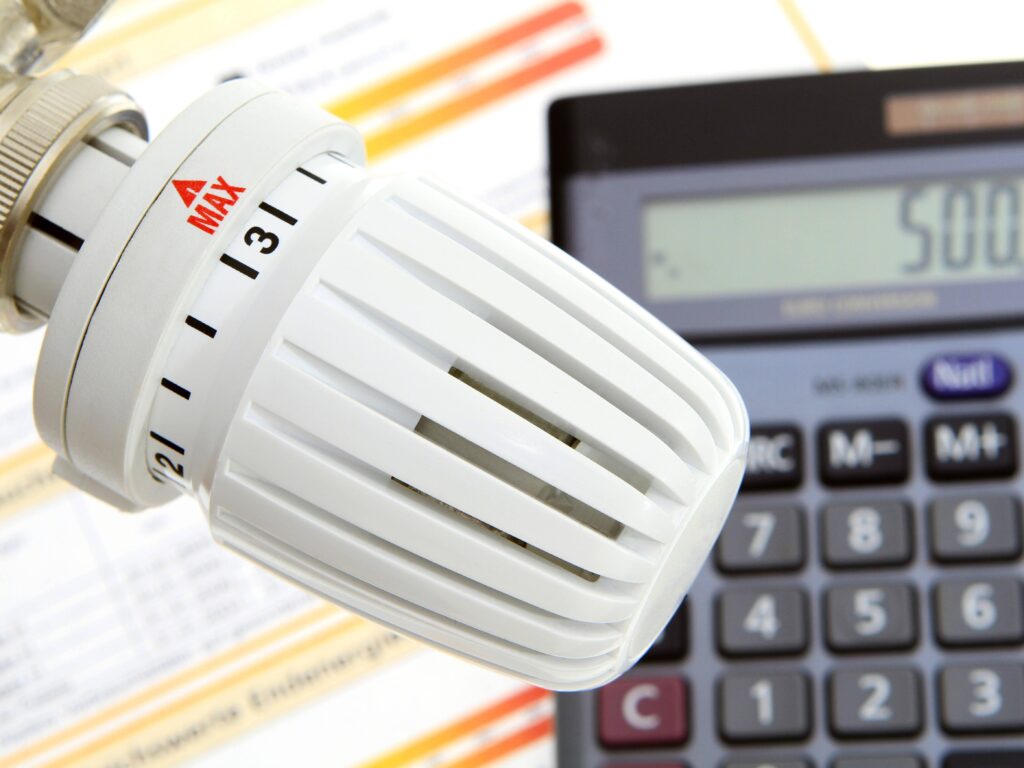 Light bulb and calculator resting on a wooden table surface.