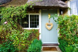 Thatched cottage with a blue door and a decorative wreath.