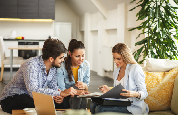 Three individuals seated on a couch, engaged with a laptop.