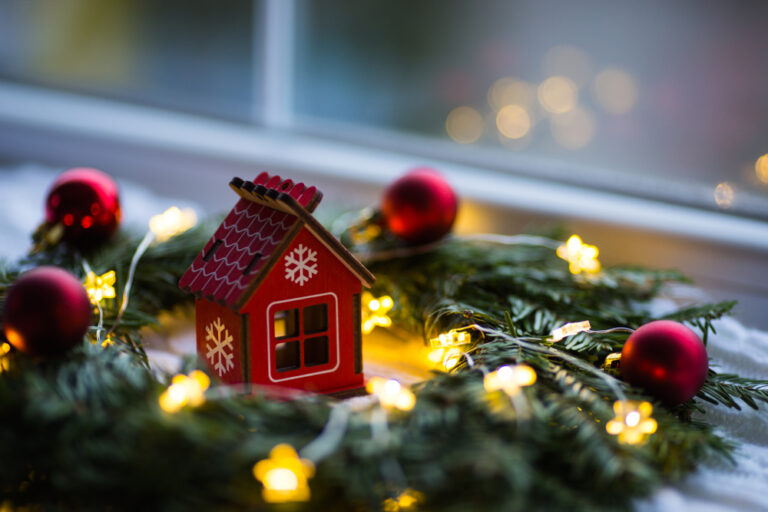 A small house atop a festive Christmas wreath.
