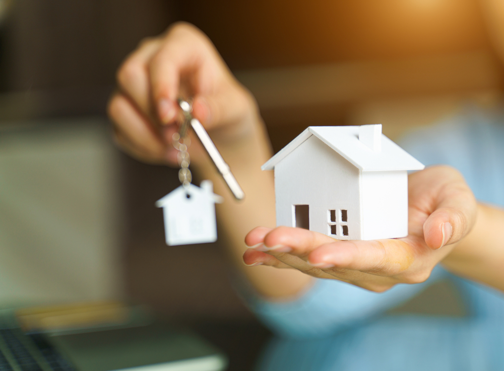 a woman holding a house and keys