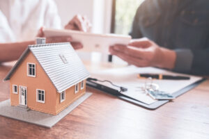 Real estate agent and client examining a house model together.