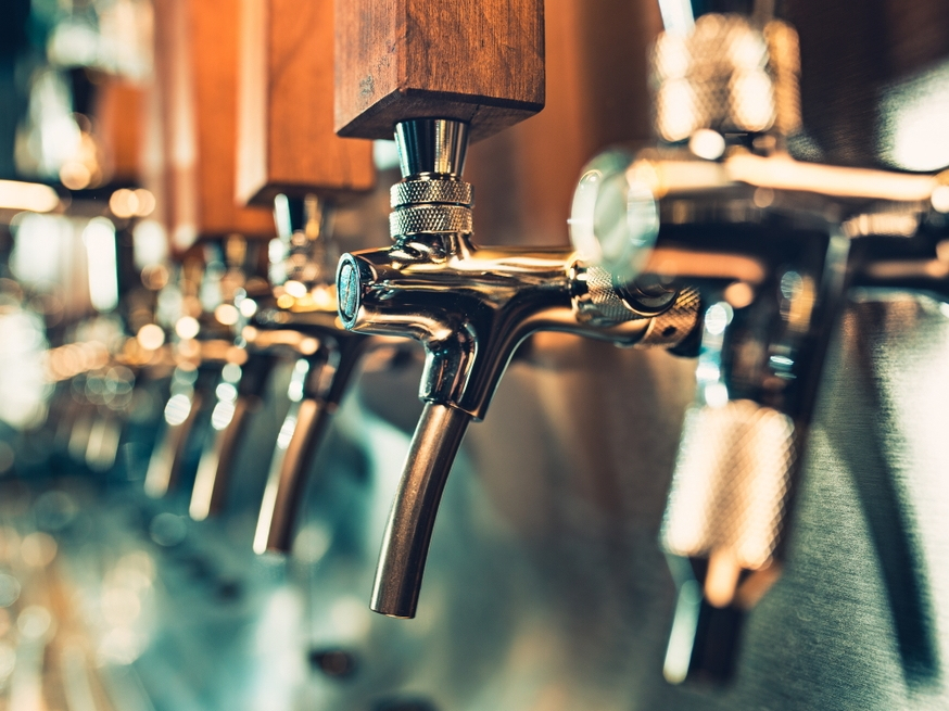 A row of beer taps mounted on a wooden wall.