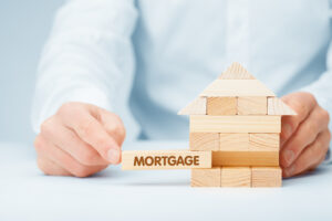 a man holding a wooden block with the word mortgage
