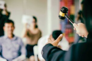 Judge with gavel addressing a group of attentive individuals.