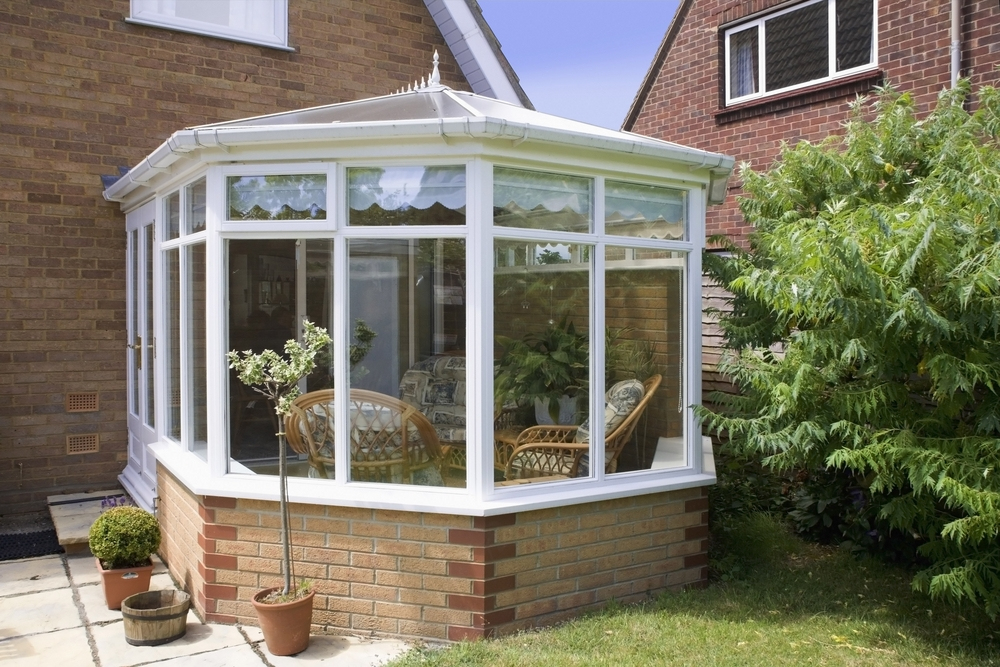 Conservatory with a patio overlooking a lush garden.