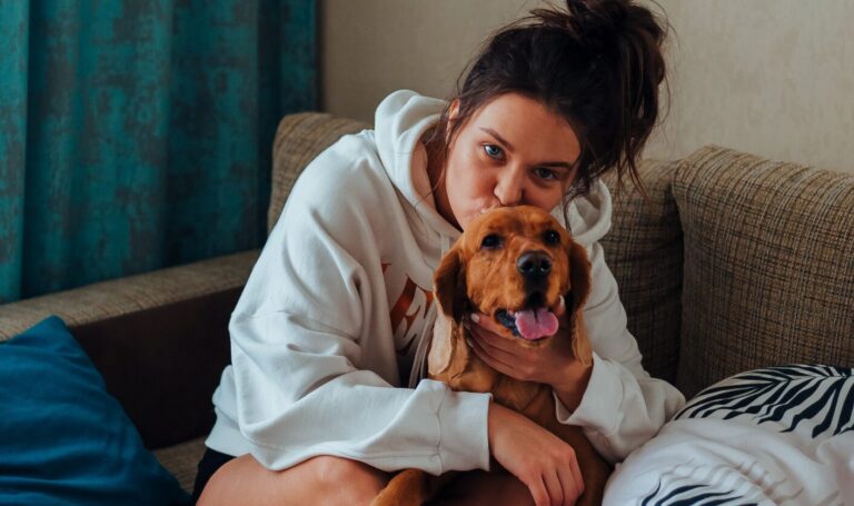 Tenant sitting on a sofa cuddling a small dog in a rented home, reflecting new 2026 rules allowing tenants to request permission to keep pets
