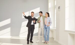 Estate agent showing a rental property to a couple, representing landlords seeking professional property management support.
