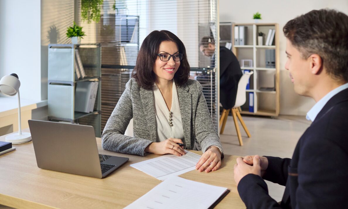 Estate agent advising a buyer at a desk, representing premium Long Ashton property searches and sought-after village streets.