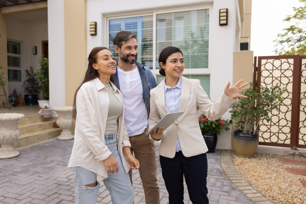Estate agent showing a property to a couple outside a home in Southville while discussing the local housing market.