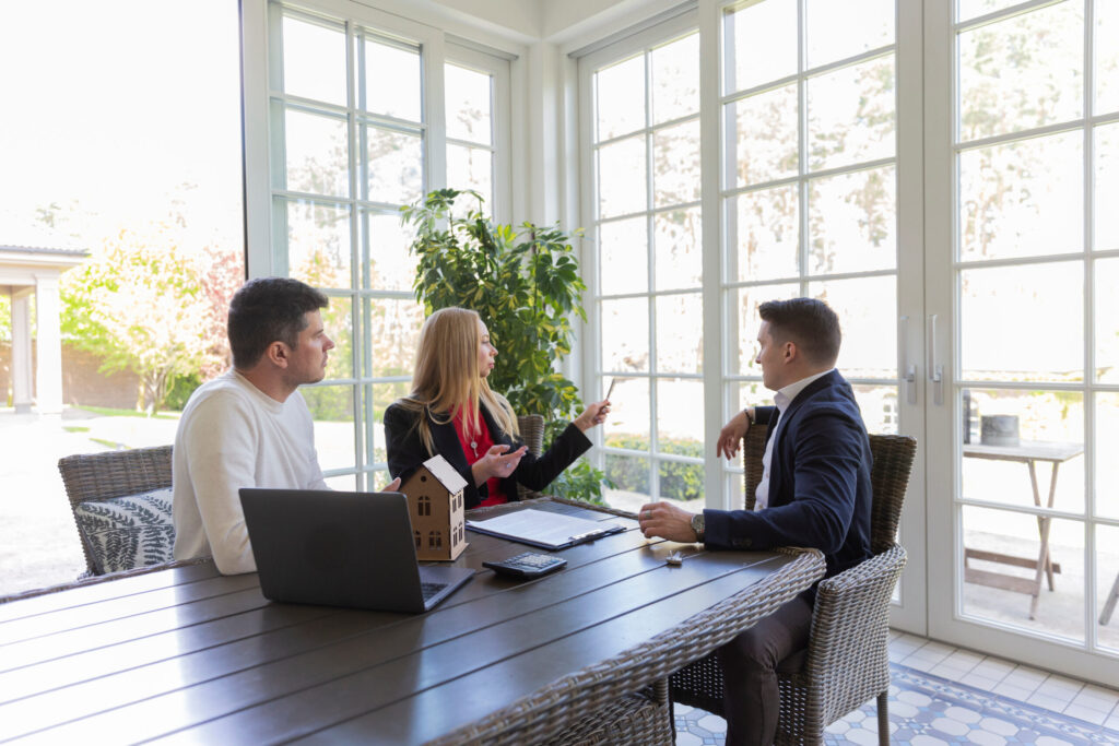 Estate agent meeting with homeowners to discuss property values and the Long Ashton housing market in a bright residential setting.